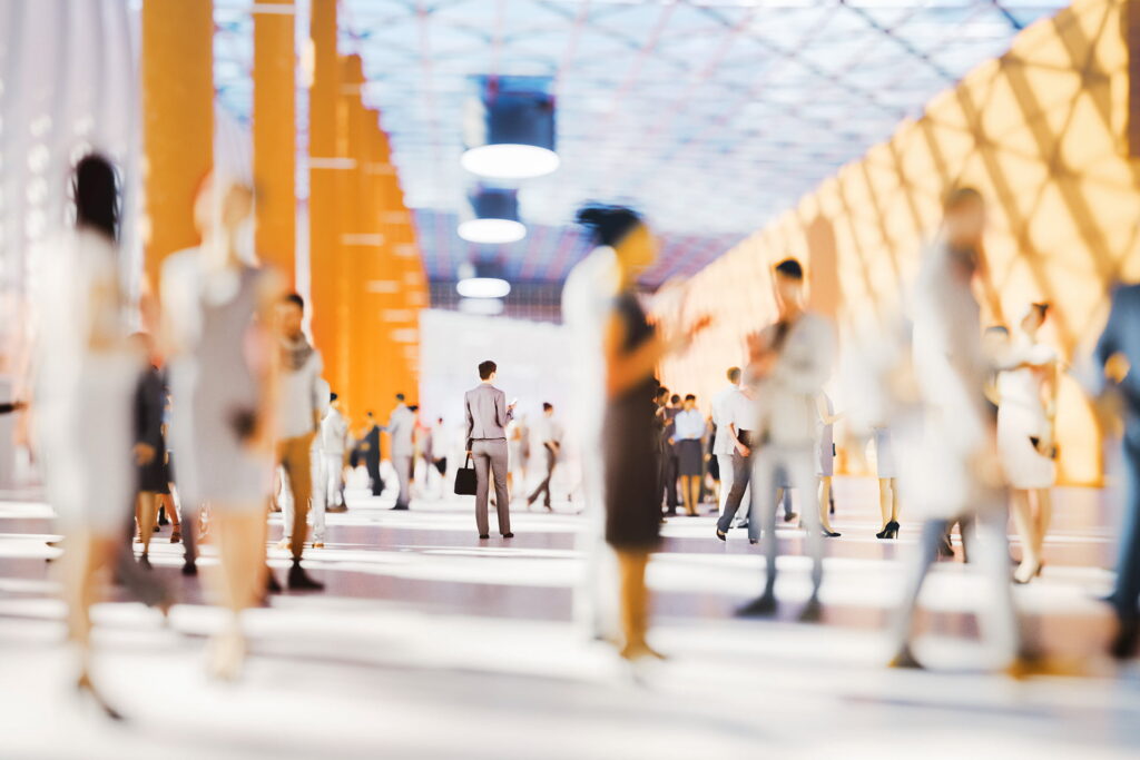 DSAG Jahreskongress 2026 1 Unschärfeaufnahme von Menschen, die sich in einem modernen, farbenfrohen Messezentrum bewegen, symbolisiert Geschäftigkeit und Vernetzung in der digitalen Welt.