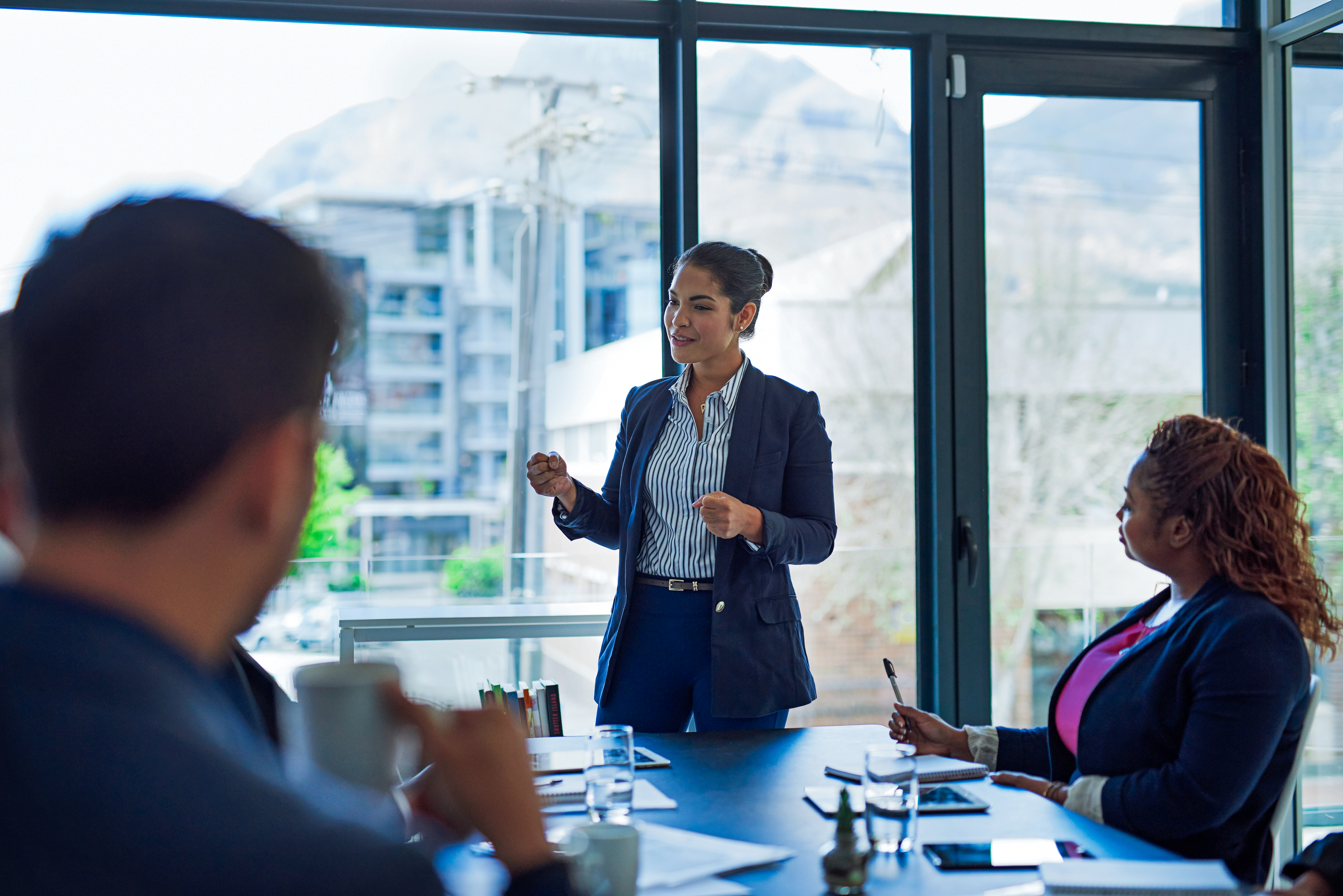 Eine Frau präsentiert in einem modernen Konferenzraum vor mehreren Zuhörern.