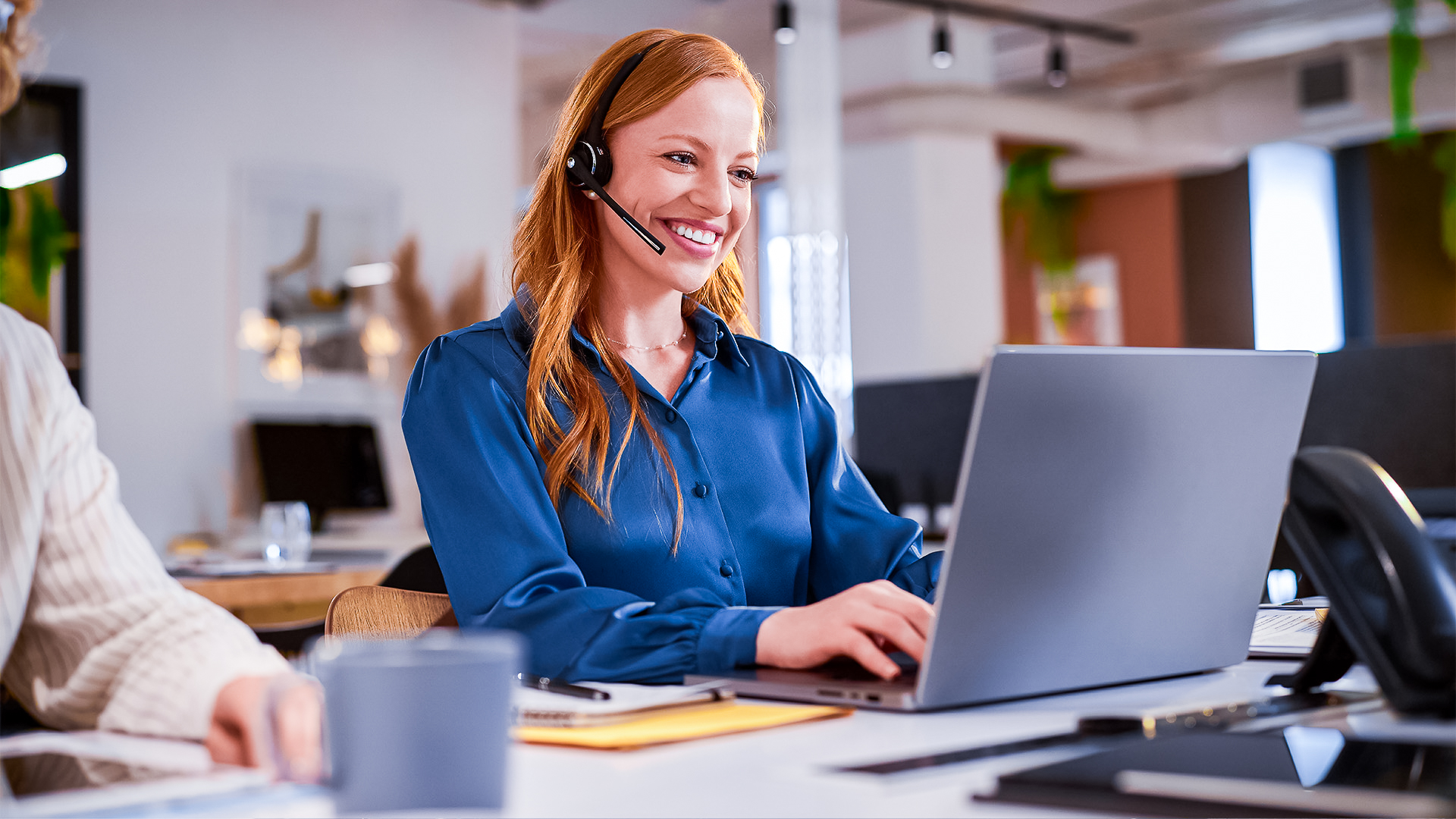Frau mit Headset am Laptop, arbeitet im Kundenservice.