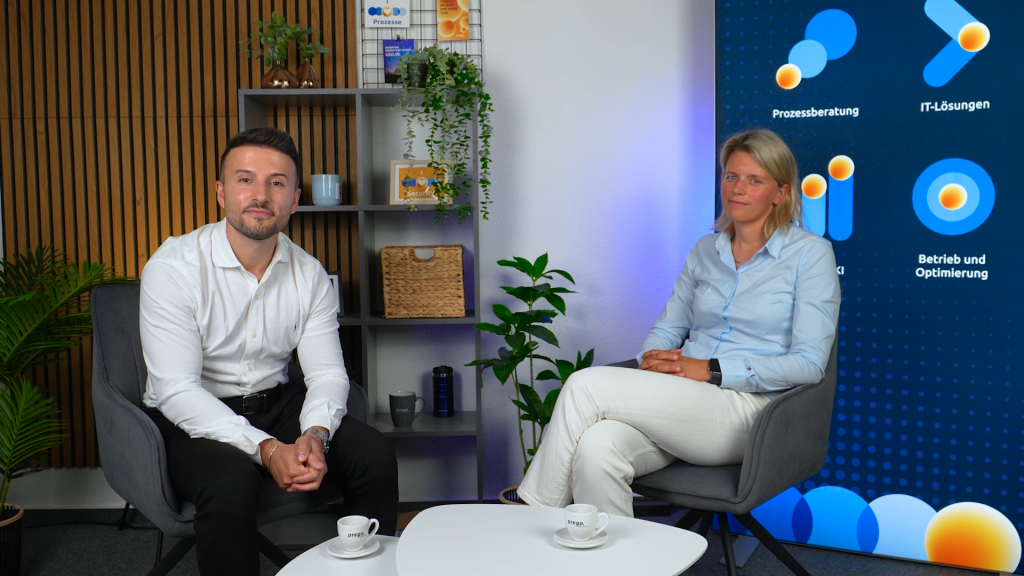 Forderungsmanagement im Wandel: Warum Energieversorger jetzt umdenken sollten 1 Zwei Fachleute im Gespräch über digitales Forderungsmanagement im Energieversorgungsumfeld, umgeben von Pflanzen und modernen Möbeln.
